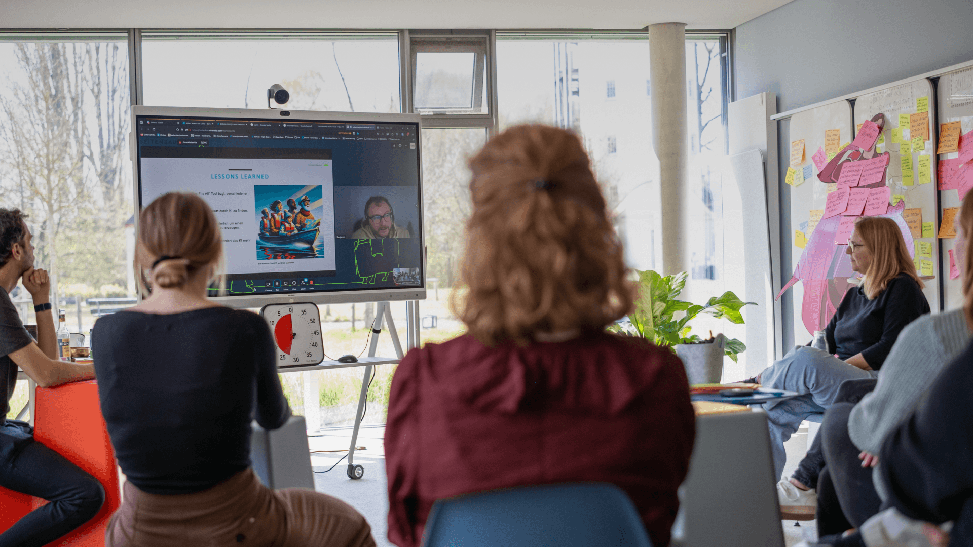 Eine Gruppe von Mitarbeitenden sitzt im Kreis und hält ein Meeting