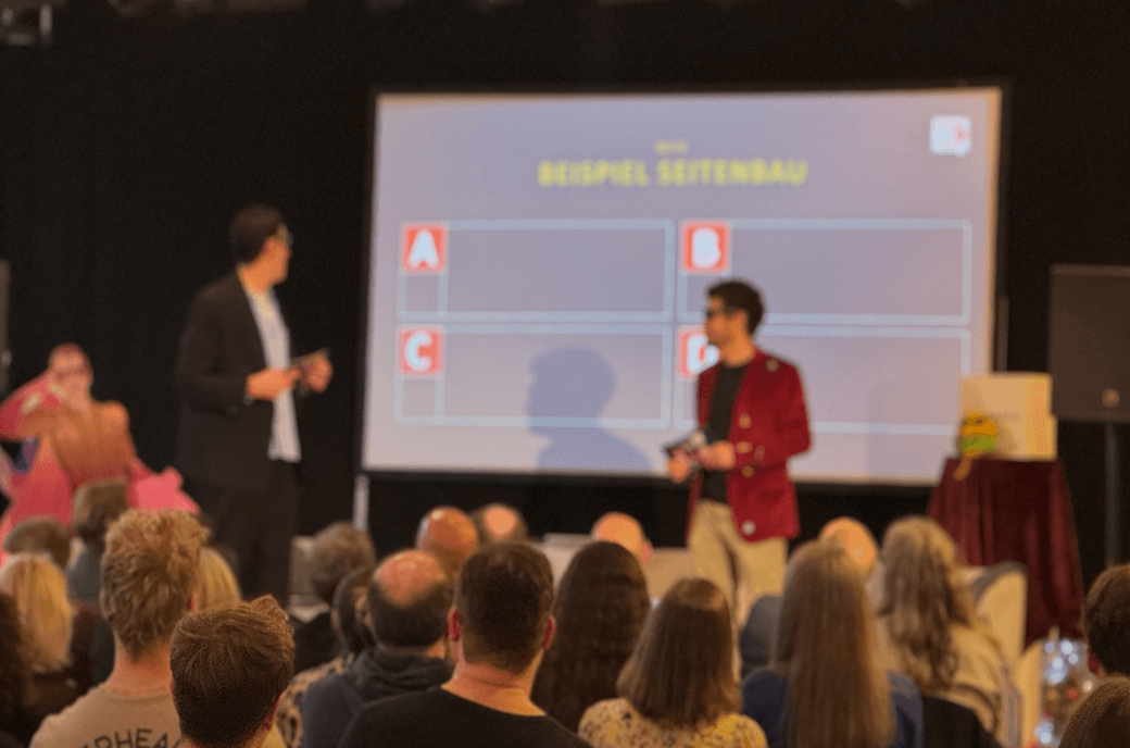 Menschen schauen auf eine Bühne mit 2 Männern