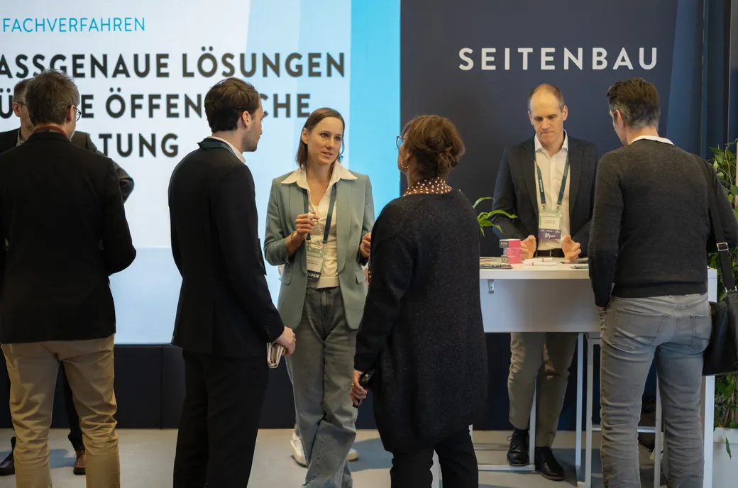 Mehrere Personen stehen am Messestand und unterhalten sich