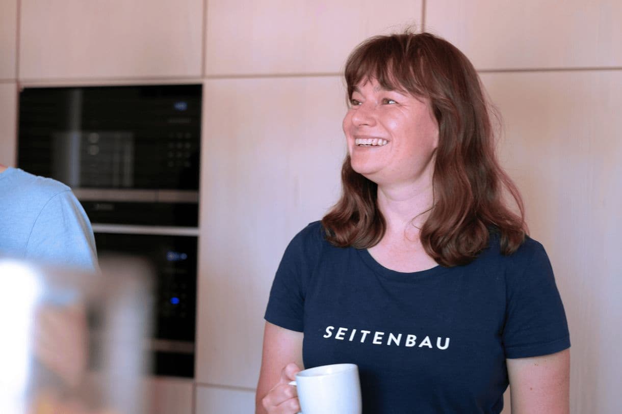 Mitarbeiterin steht in der SEITENBAU Küche und lacht