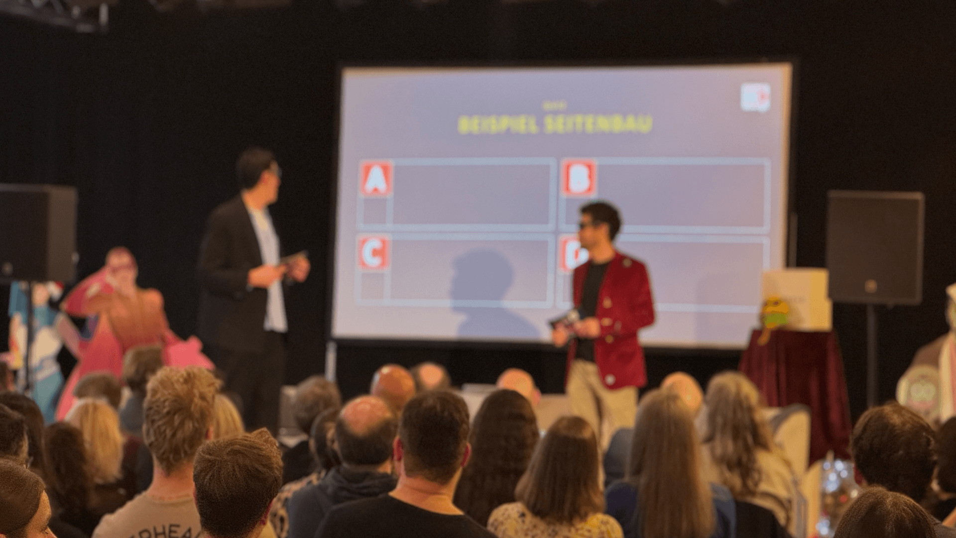 Menschen schauen auf eine Bühne mit 2 Männern