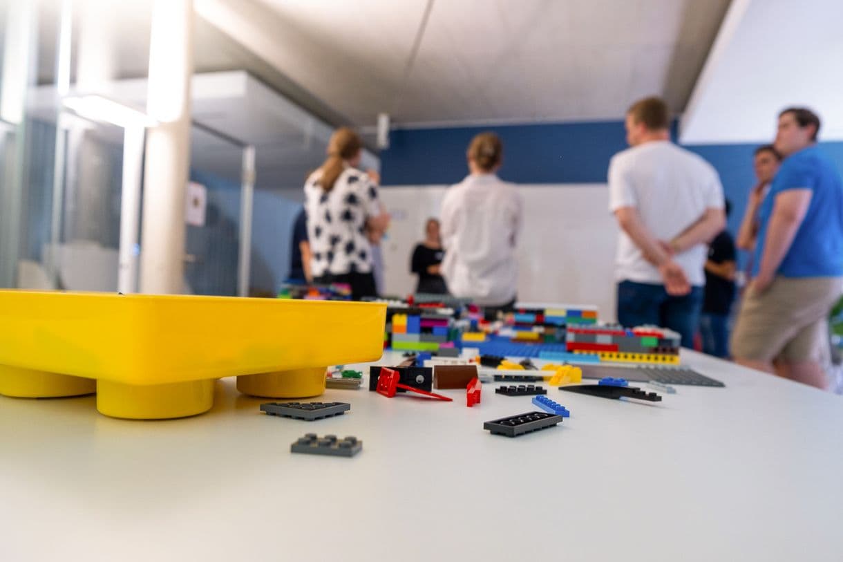 Gruppe von Menschen im Hintergrund, Legosteine im Vordergrund