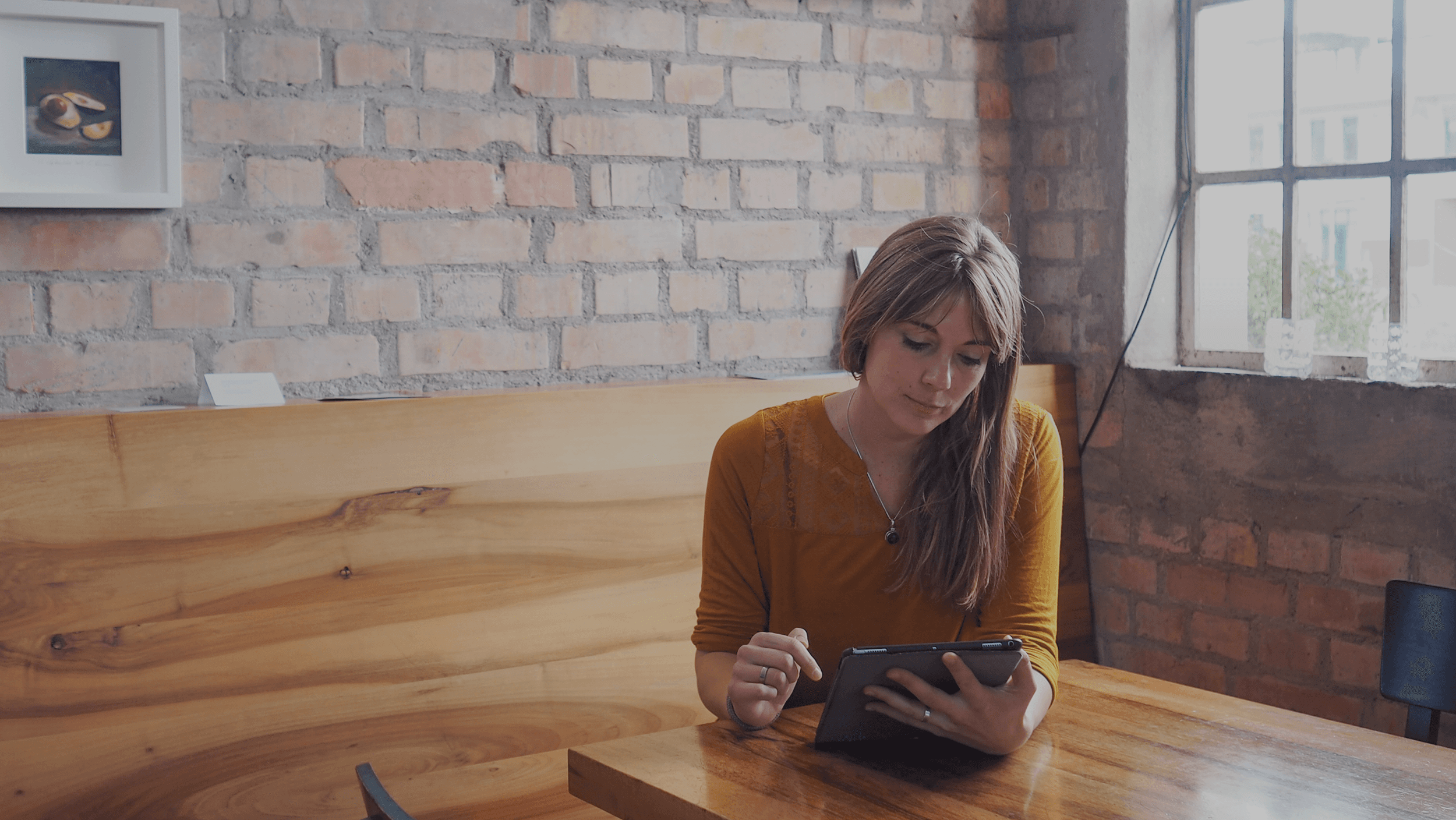 eine frau sitzt auf einer holzbank und schaut auf ein tablet