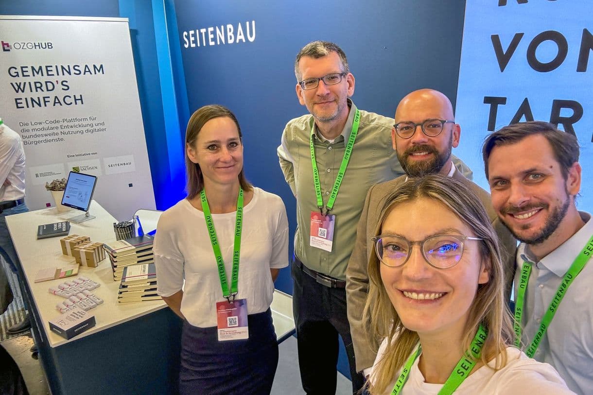 ein Gruppe Mitarbeitende vor dem Messestand am Zukunftskongress 2025